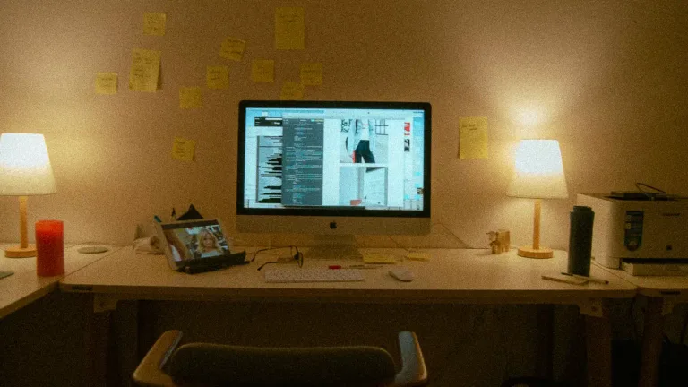 Workspace with monitor, desk lamps and sticky notes for content planning