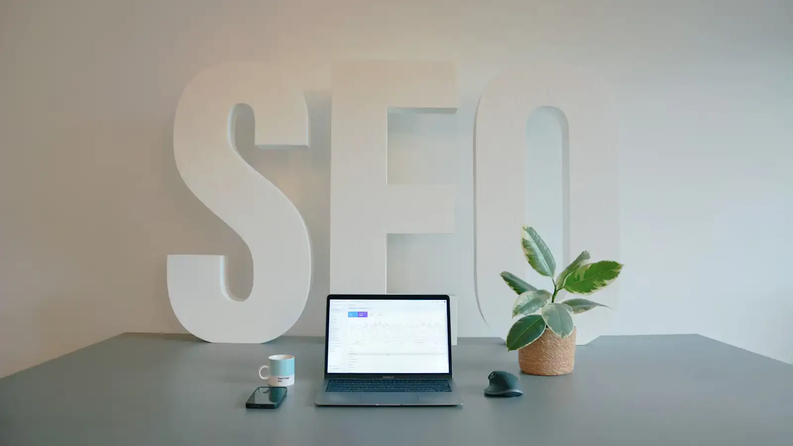 Desk with laptop and large SEO letters in the background