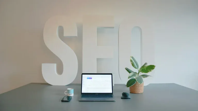 Desk with laptop and large SEO letters in the background