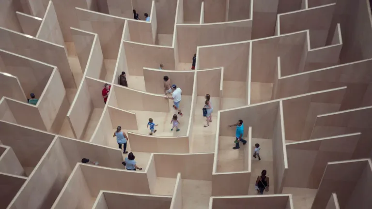 People walking through a large light-colored maze seen from above